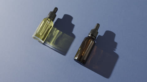 Close-up-of-two-glass-bottles-with-pumps-with-copy-space-on-blue-background