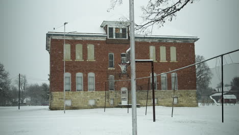 snowflakes fall in cinematic slow motion on old abandoned building and the ground and trees during winter snow storm