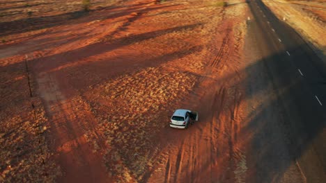 orbiting aerial view of a car on a roadside near alice springs in the early morning, nt - australia