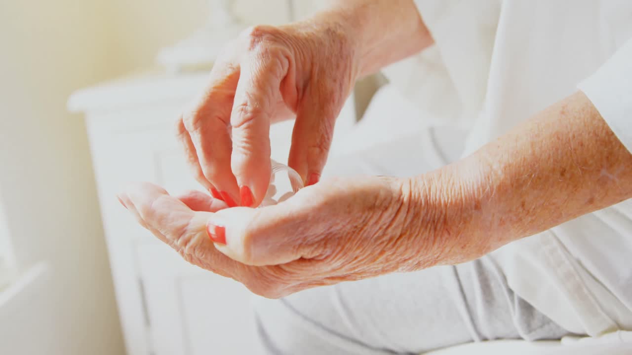 편안한 집의 침실에서 약병에서 약을 꺼내는 고령 여성의 클로즈업 4k