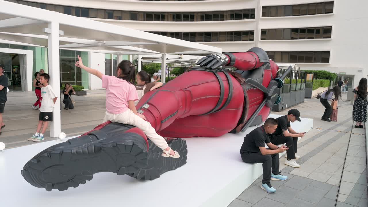 Children pose on an 8-meter Marvel Deadpool installation as locals and tourists take photos. The display promotes Disney's movie "Deadpool and Wolverine" in Hong Kong.