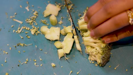 hands of young asian woman carefully cutting broccoli on cutting board