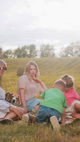 familia feliz reunida en una manta a cuadros en el campo abierto, disfrutando de un picnic al aire libre con bocadillos, la luz del sol proyecta un brillo cálido, con balas de heno y árboles en el fondo