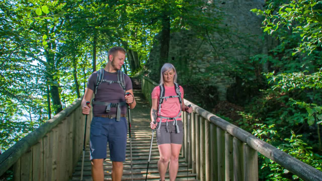 Boy and girl walking towards the camera on a wooden bridge. Beautiful sunny day. Green window, Slovenia