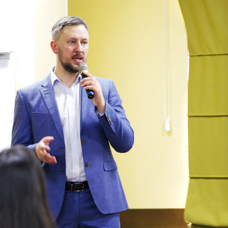 successful manager conduct a meeting. handsome businessman talks into a microphone during the public seminar in auditorium.