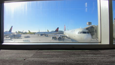 airport terminal window showing airplanes waiting at the gate sunny day at miami international airport, ground staff handling baggage and services, located on miami, florida, usa, time lapse