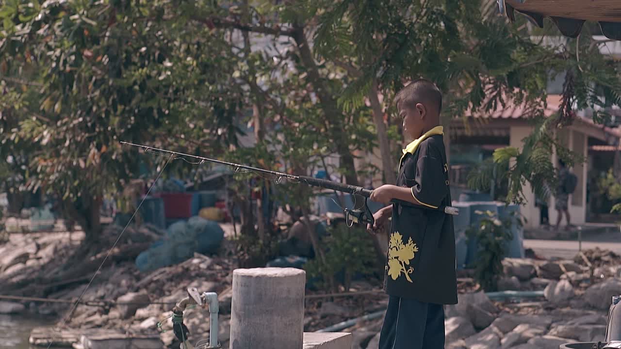 bambino in maglietta gialla nera gira la bobina sollevando la barra marrone