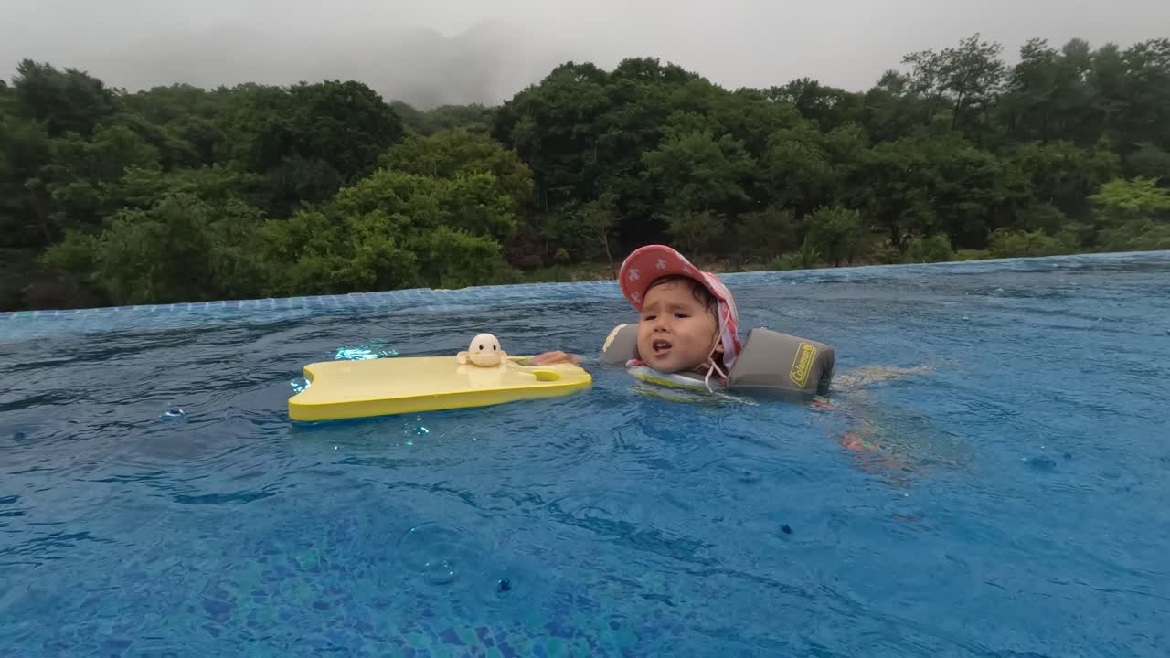 3 Year Old Child Girl Lean Swimming in Outdoor Pool on Rainy Day
