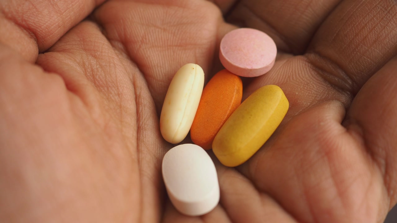 Hand Holding Assorted Colorful Pills and Supplements