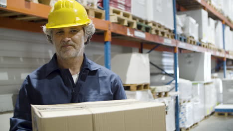 caucasian male worker holding cardboard box and looking at the camera