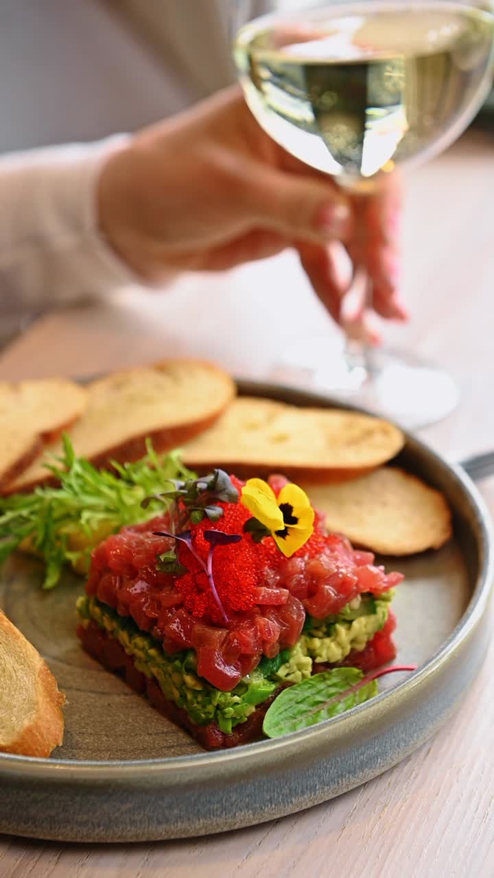 Tuna tartare with avocado mousse and red caviar garnish. Square tuna tartare layered with avocado served with toasted bread slices and edible flowers