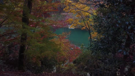 autumn japanese scene as boat travels on blue katsura river