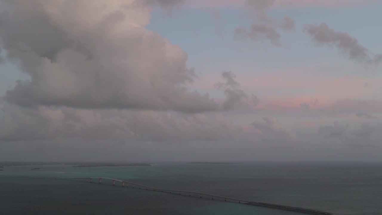 Horizontal cameo shot tilting down from an upward-facing view of the clouds toward the ocean and coastline of Irabu Island, Miyako, Okinawa, Japan