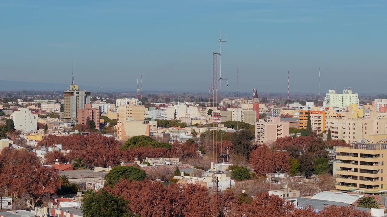 Un video con drone riprende un'imponente torre di telecomunicazioni che si erge sopra lo skyline urbano, con cieli sereni, fogliame autunnale e vivaci dettagli della città di San Juan