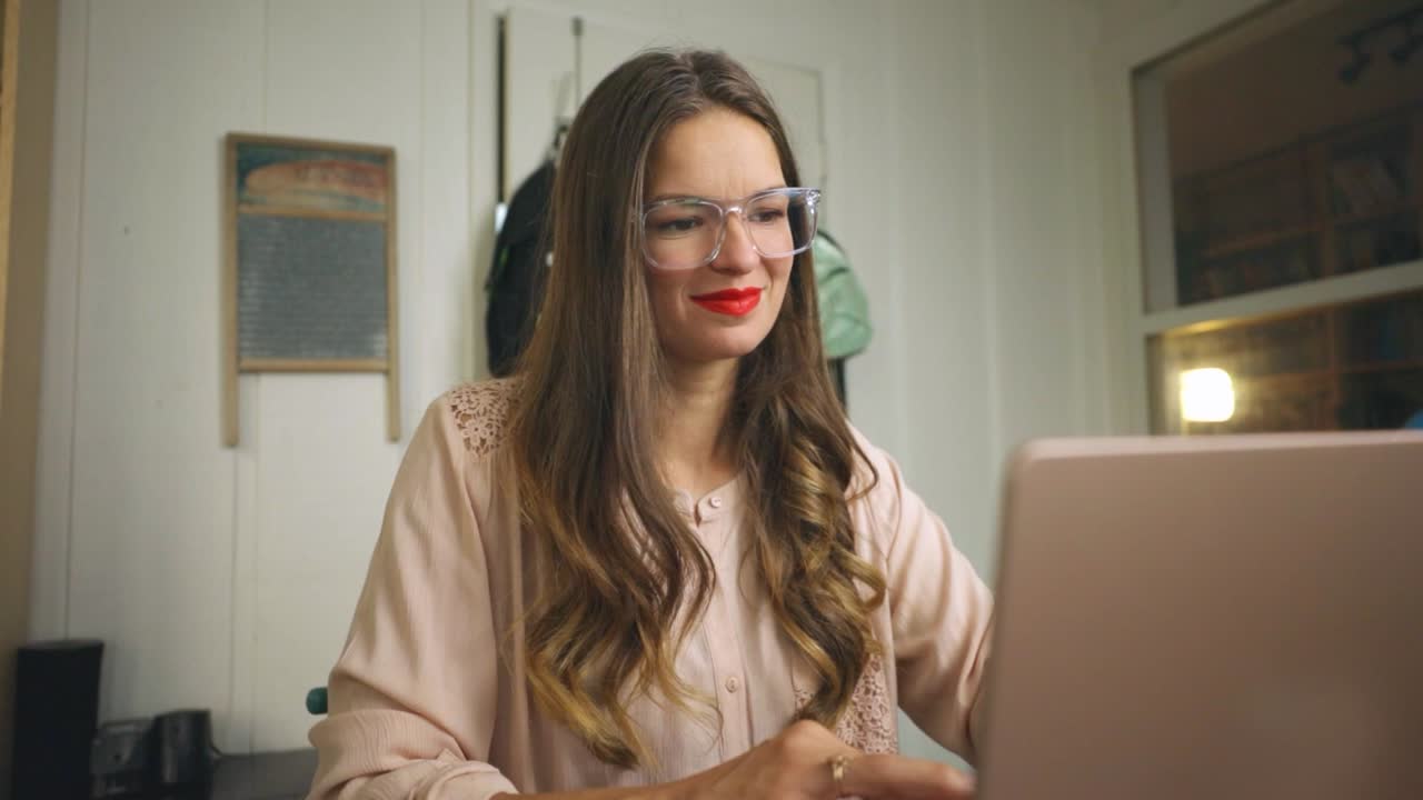 Donna con gli occhiali che lavora da casa al computer portatile