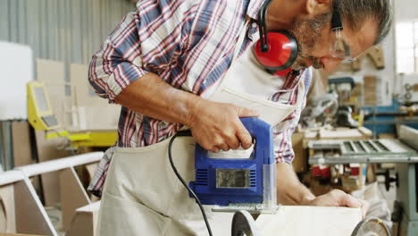 Side view of carpenter sawing a wood plank