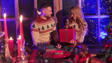 man is giving a present to his blonde girlfriend. couple in love celebrating christmas in country house.