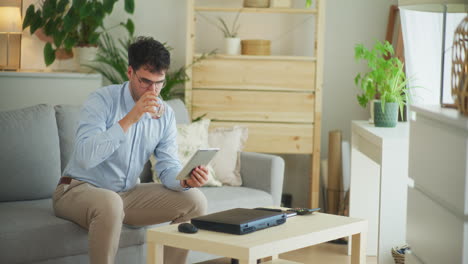 Businessman-Drinks-Water-While-Working-on-Tablet