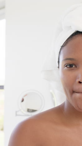 vertical video of portrait of happy african american wearing towel on head, slow motion