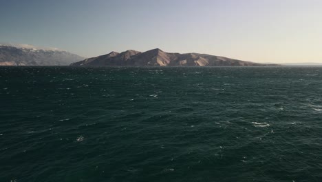 low altitude straight plane with drone in baska croatia with wonderful view of the blue sea and a blue sky to the horizon a large mountain centered in the plane bathed in the sun 4k