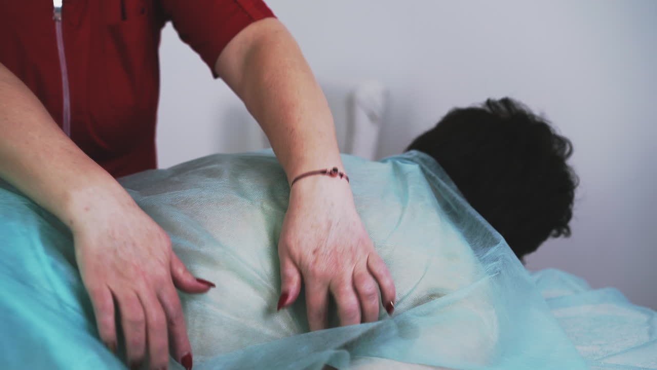 el médico en uniforme limpia a la mujer de la miel en el sofá.