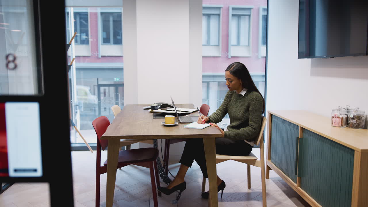 Businesswoman Working On Laptop At Desk In Meeting Room