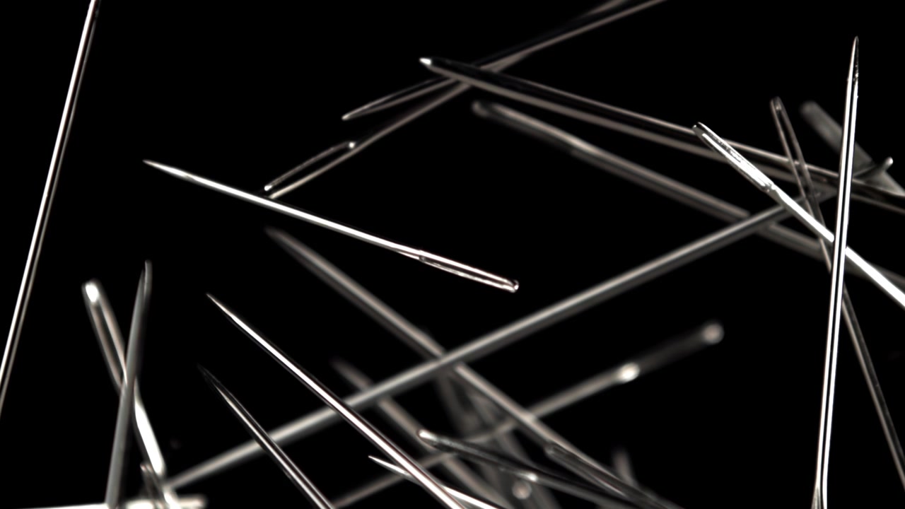Metallic Sewing Needles Falling in Slow Motion on Black Background