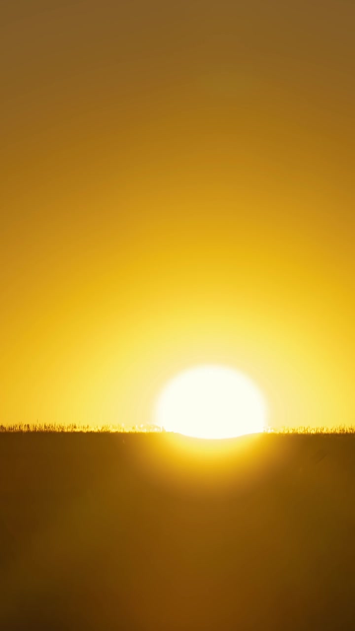 Aikaviivekuva kultaisesta auringonlaskusta pellon yllä.