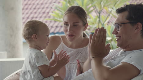 parents teaching baby clapping hands