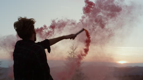 Man-dancing-in-mountains-at-sunset-with-smoke-flare