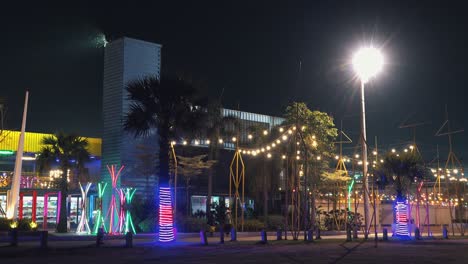 toma mediana de un parque de diversiones colorido hecho de contenedores con gente caminando frente a él en la noche