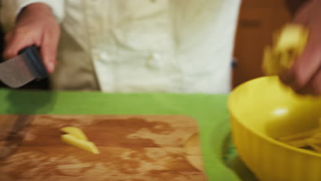 chefs hands cut long italian potatoes into sticks to fry them