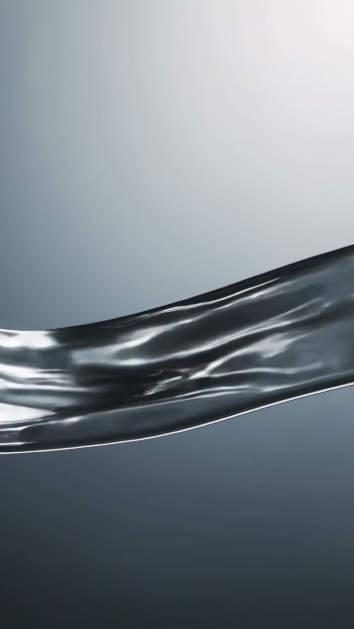 Vertical video: Entering left, silver ribbon sliding right across gray backdrop, catching top light