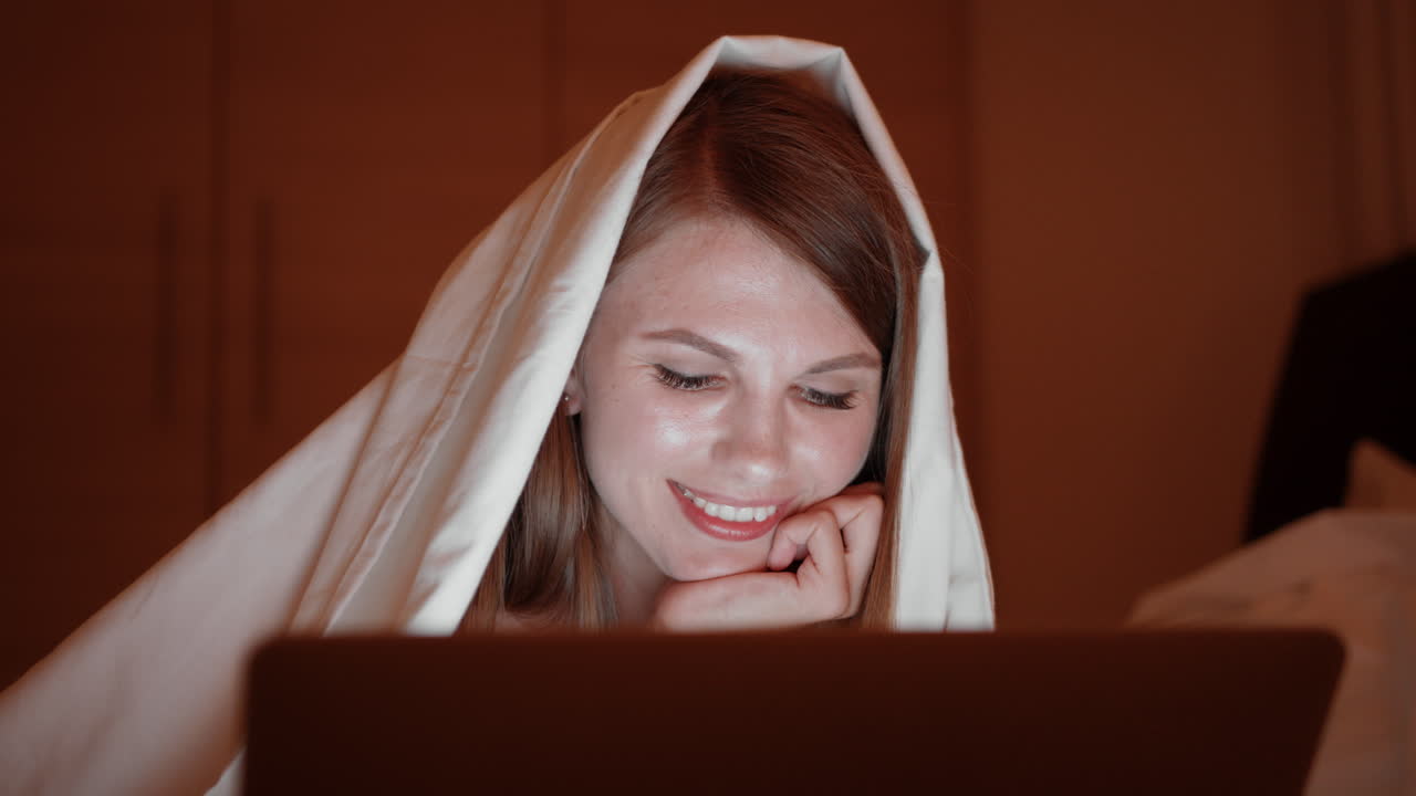 женщина работает на ноутбуке в постели ночью