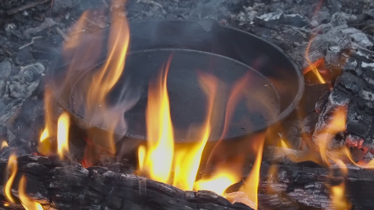 오렌지색 불꽃이 주조 철 비를 둘러싸고 있습니다. 열린 불에 맛을 내고 있습니다.