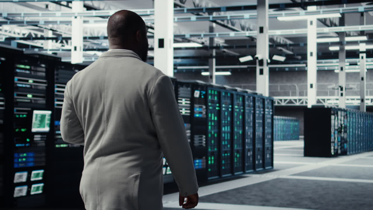 Vertical video Engineer walking in server farm, automating system diagnostics
