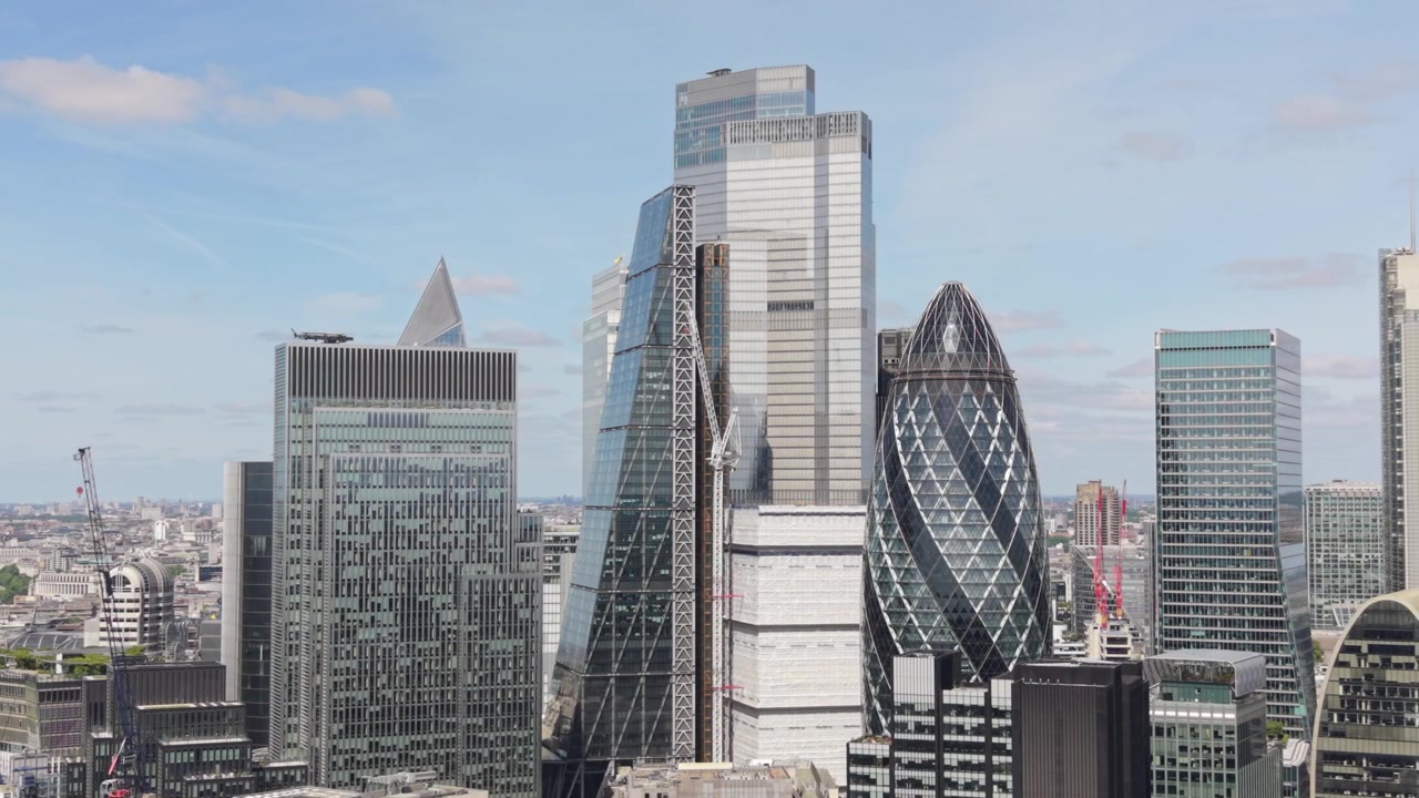 Exibindo o icônico horizonte da cidade de Londres em um dia claro e ensolarado. Arranha-céus modernos dominam o distrito financeiro, incluindo The Gherkin e The Leadenhall Building, sob um céu azul claro