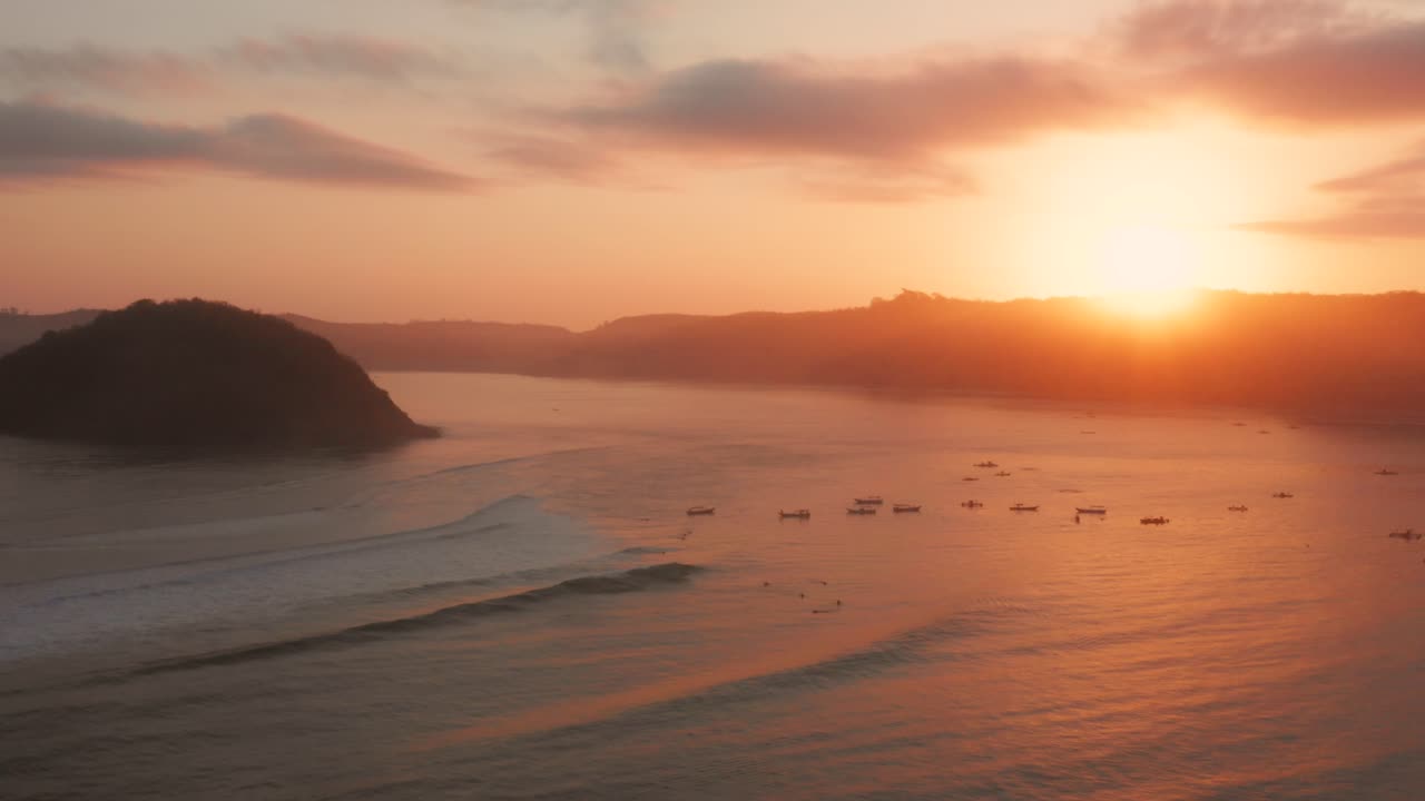 롬복에 있는 게루푹의 서핑 장소에서 일출, 어선과 서퍼가 있는 만의 전망