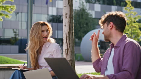 friends laughing urban park closeup. smiling couple working remotely chatting