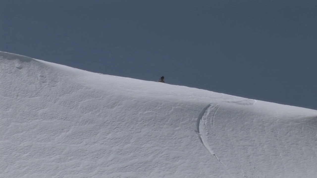 siguiente toma de un snowboarder mientras desciende lentamente por una pendiente de polvo virgen