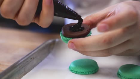 pastry chef fills french macarons with chocolate filling, close up slow motion 4k