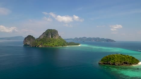 half turn drone shot of several small islands in the middle of a gorgeous colourful ocean