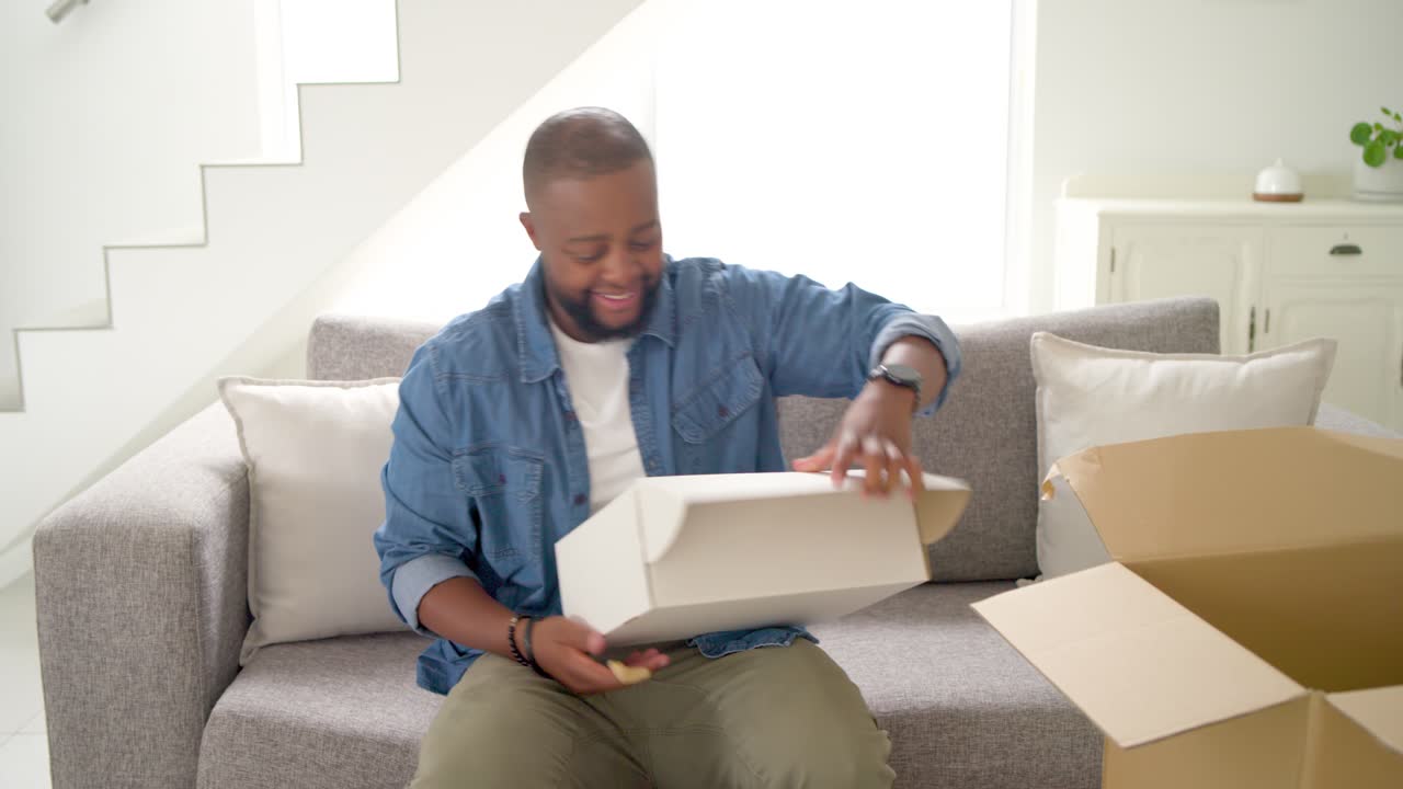 African American man opening shipping box at home pulling white box revealing order in blue tissue