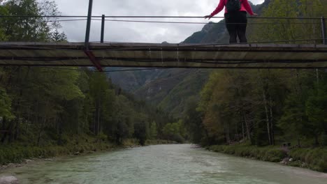 Woman-watching-breathtaking-view-of-Soca-valley-on-suspension-bridge-at-Slovenia,-aerial