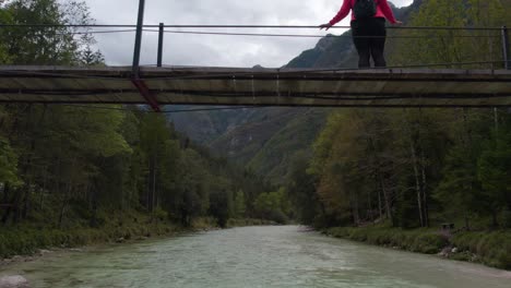 woman watching breathtaking view of soca valley on suspension bridge at slovenia, aerial