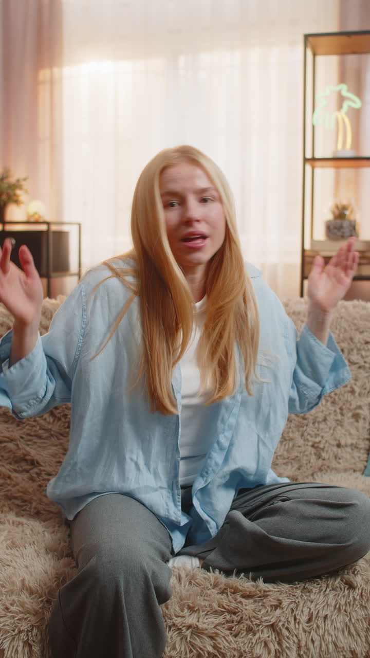 Young woman clueless shrug at home arms spread doubt uncertain look confused mood no answer