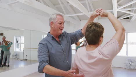 parejas de ancianos caucásicos pasando tiempo juntos en un salón de baile y bailando