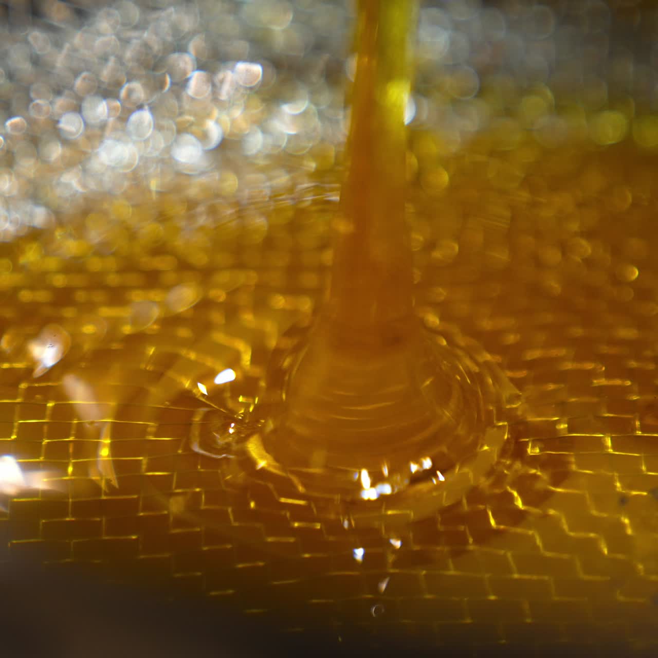 Unfiltered fresh honey flows on the metal sieve. Close up. Healthy organic food production at apiary
