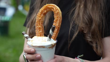 primer plano que muestra a una chica sosteniendo un tentador vaso de batido de churro de pie al aire libre