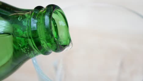 pouring sparkling water from green bottle into glass